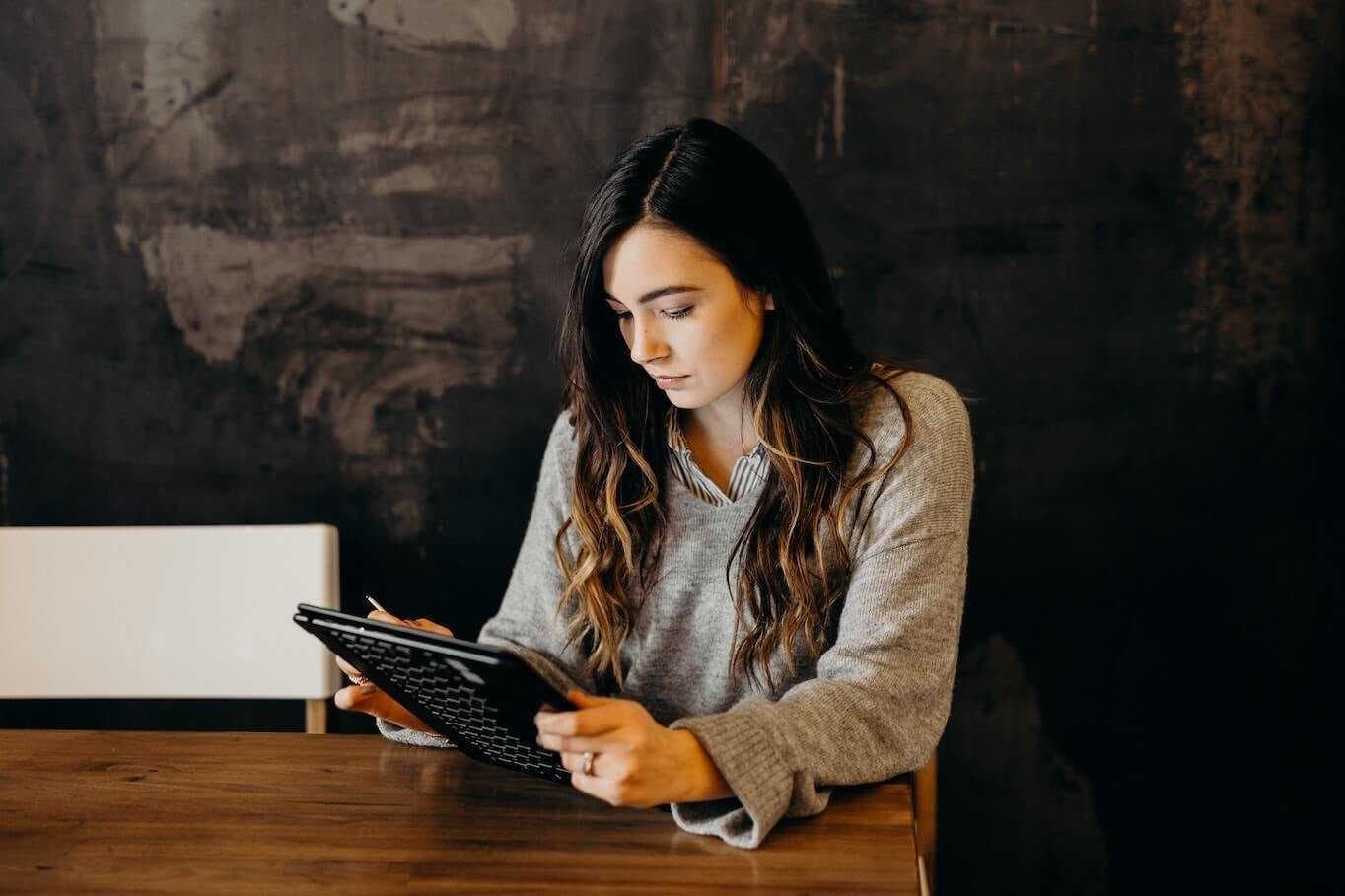 Woman holding tablet behind desk